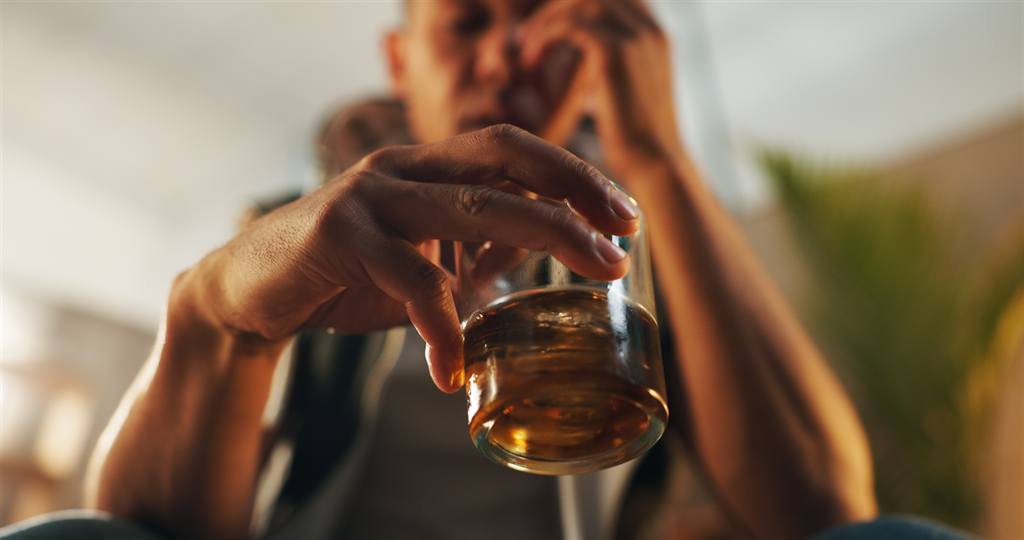Mão masculina segurando um copo de bebida alcoólica