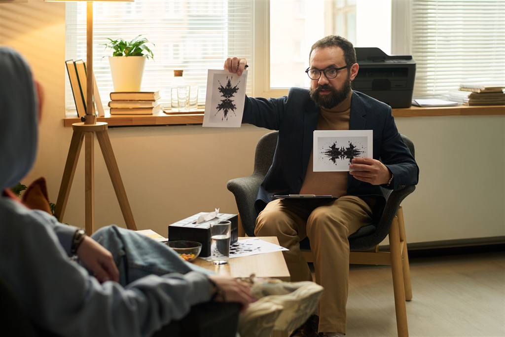 Psicólogo mostrando pranchas de manchas de tinta em uma consulta