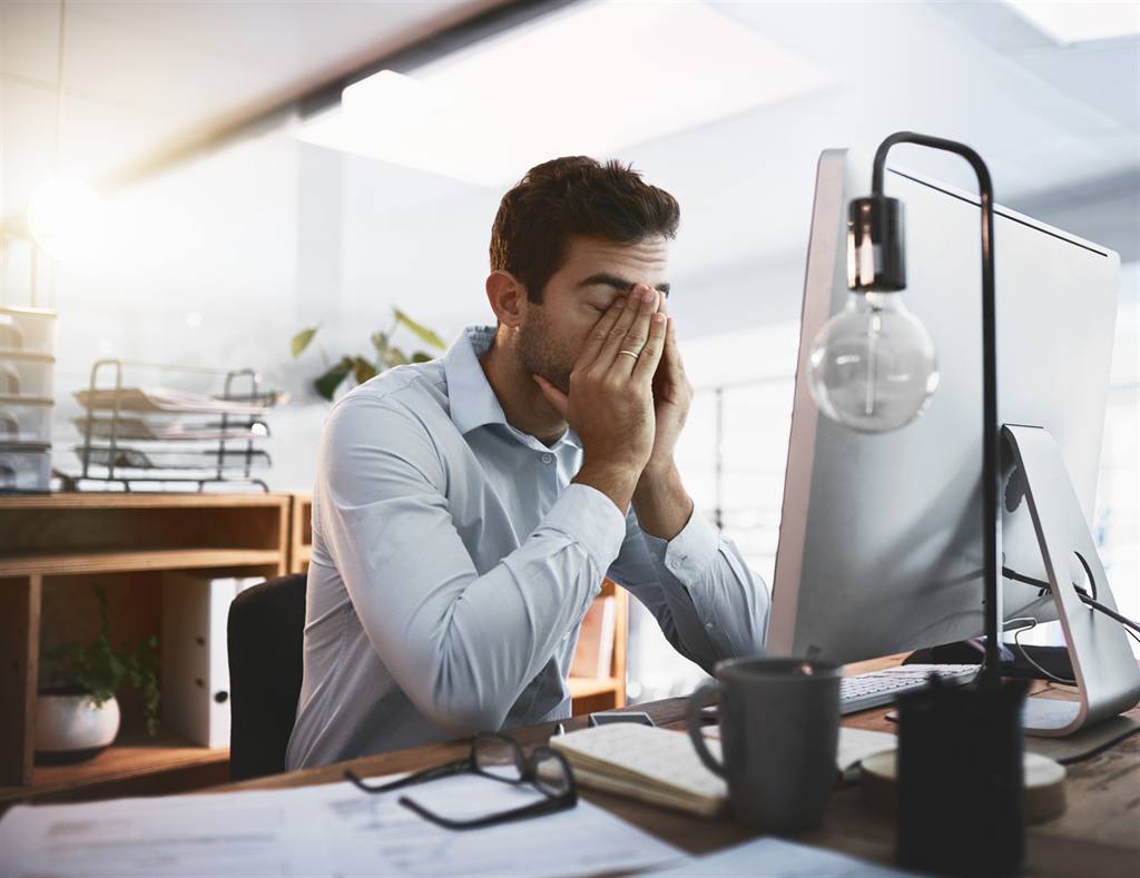 Homem exausto diante do computador no escritório